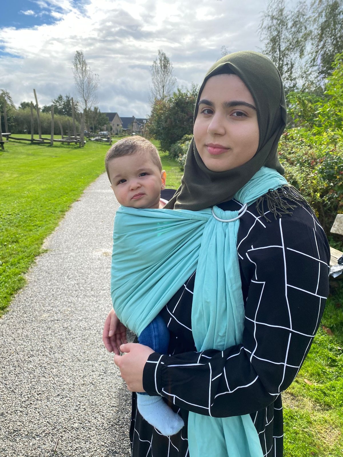 Kind in een turquoise ringsling, buiten
